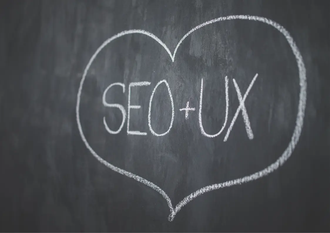UX plus SEO dans un coeur dessiné à la craie blanche sur un tableau noir.